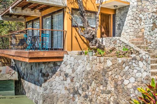 a stone house with a porch and a stone wall at Atitlan Sunset Lodge in Santa Cruz La Laguna