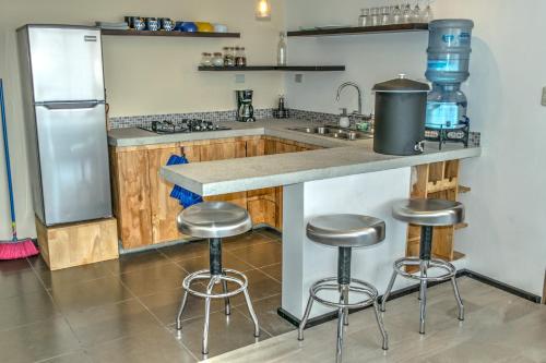 a kitchen with three bar stools and a counter at Atitlan Sunset Lodge in Santa Cruz La Laguna