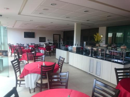 a restaurant with red tables and chairs and a counter at King Konfort Hotel in Maringá