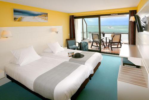 a hotel room with a bed and a view of the ocean at Albatros in Quiberon