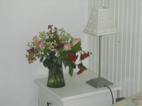 a vase of flowers on a table next to a lamp at Hotel De Waag in Bergen