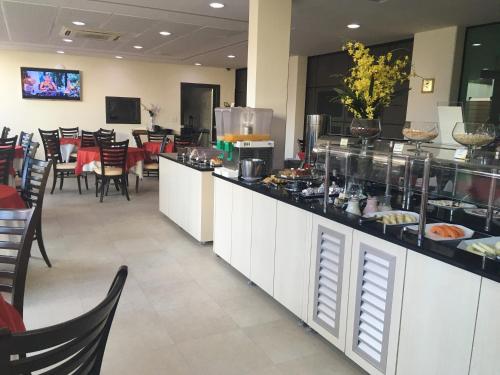 a restaurant with a counter with food on it at King Konfort Hotel in Maringá