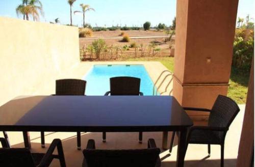 un tavolo e delle sedie davanti a una piscina di Villa prestige a Marrakech