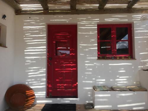 a red door and two windows on a white wall at Casa Pedralva in Vila do Bispo