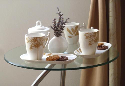 a glass table with three cups and cookies on it at Nice Apartment & Room in Cavtat in Cavtat