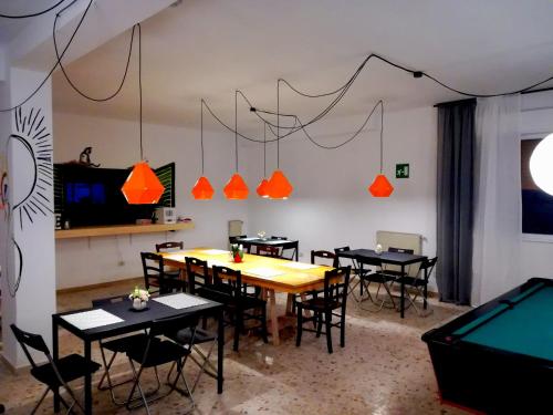 una sala da pranzo con tavoli, sedie e tavolo da biliardo di Dimora Hostel a Agrigento