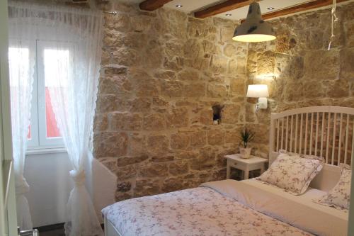 - une chambre avec un lit et un mur en pierre dans l'établissement Atlantida Apartment, à Split