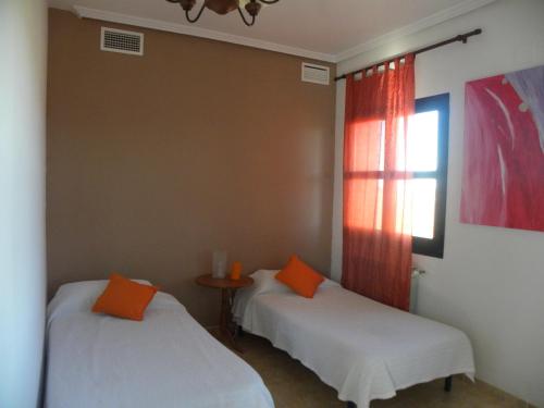 Cette chambre comprend 2 lits, une table et une fenêtre. dans l'établissement El Jardin de los Gatos Apartament, à Cáceres