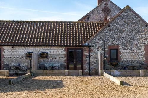 an old stone building with a patio in front of it at Briarfields Hotel in Titchwell