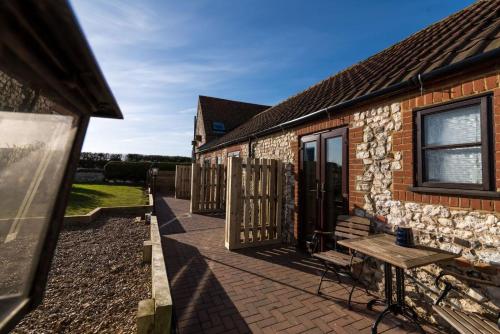 a stone house with a bench on a patio at Briarfields Hotel in Titchwell