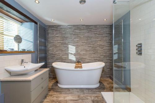 a bathroom with a tub and a sink and a shower at Briarfields Hotel in Titchwell