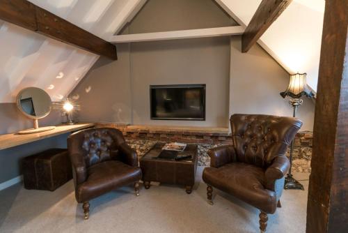 a living room with two chairs and a tv at Briarfields Hotel in Titchwell