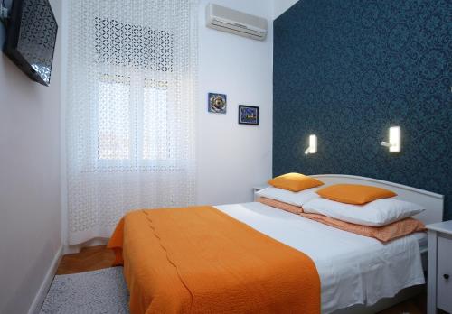 1 dormitorio con 1 cama con manta naranja en Apartments Marmont, en Split