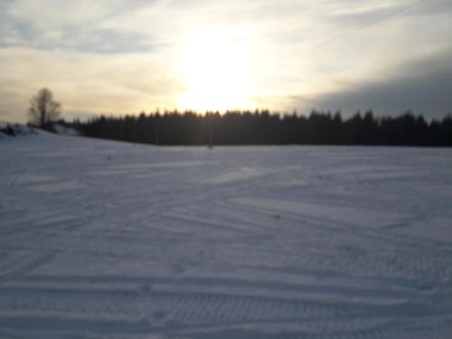 a snow covered field with the sun in the background at Ferienwohnung Panoramablick in Bärenstein