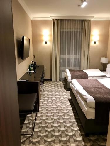 a hotel room with two beds and a desk at Hotel Mansor in Ząbki