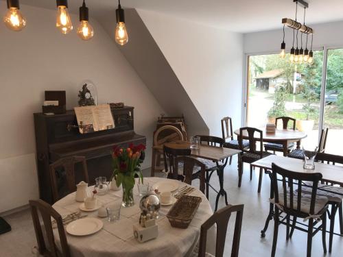 une salle à manger avec des tables, des chaises et un piano dans l'établissement La Nicoulette, à Gapennes