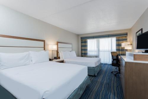 a hotel room with two beds and a flat screen tv at Wyndham Virginia Beach Oceanfront in Virginia Beach