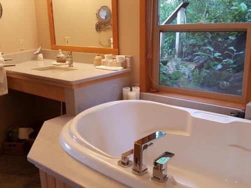 un bagno con vasca, lavandino e finestra di Reef Point Oceanfront Bed and Breakfast a Ucluelet