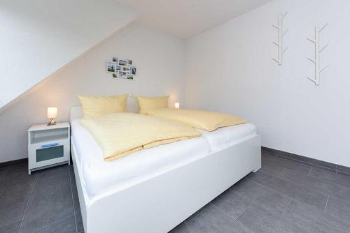 ベンサージールにあるFerienwohnung ANKERmalのサイドテーブル付きの白い部屋の白いベッド
