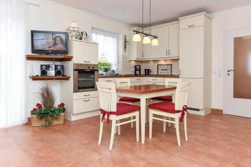 uma cozinha com mesa e cadeiras e uma televisão em Haus Benser Riff em Bensersiel
