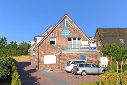 two cars parked in front of a brick house at Ferienwohnungen Am Sieltor in Bensersiel