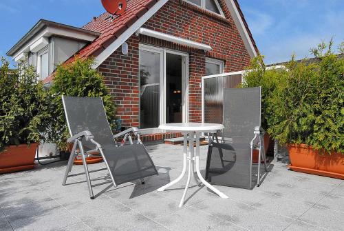 uma mesa e duas cadeiras sentadas fora de uma casa em Haus Benser Riff em Bensersiel