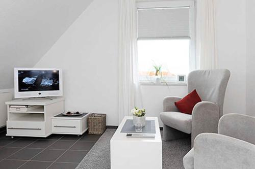 ein Wohnzimmer mit einem Sofa und einem TV in der Unterkunft Nordseegartenpark Nordseestolz in Bensersiel