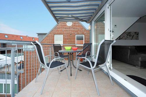 a patio with a table and chairs on a balcony at Nordseegartenpark Nordsee_Panorama in Bensersiel