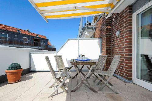 a wooden table and chairs on a balcony with a roof at Urlaubswelt Nordseegartenpark in Bensersiel