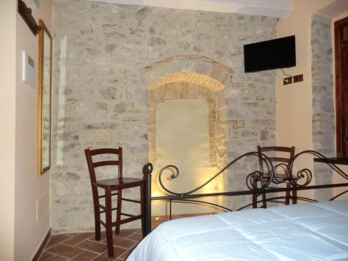 1 dormitorio con 1 cama, 2 sillas y TV en Residenza Frenguelli en Spello