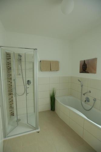 ein weißes Bad mit einer Badewanne und einer Dusche in der Unterkunft Ferienwohnung Gentner Fulda in Fulda