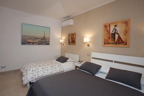 een slaapkamer met 2 bedden en een schilderij aan de muur bij Trio D'Archi - Elegant Loft Caltagirone in Caltagirone