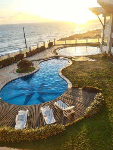 a swimming pool with two lounge chairs and the ocean at EmanuelleSales - Corretora de Imóveis - "LUXURY RESIDENCES" creci 16949F in Canoa Quebrada