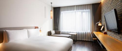 a hotel room with a white bed and a chair at Maison Glad Jeju in Jeju