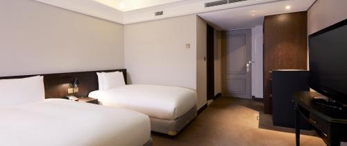 a hotel room with two beds and a flat screen tv at Maison Glad Jeju in Jeju
