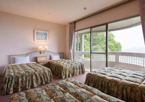 a hotel room with two beds and a large window at Izumigo Hotel Altia Toba in Toba