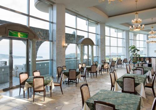 a dining room with tables and chairs and windows at Izumigo Hotel Altia Toba in Toba