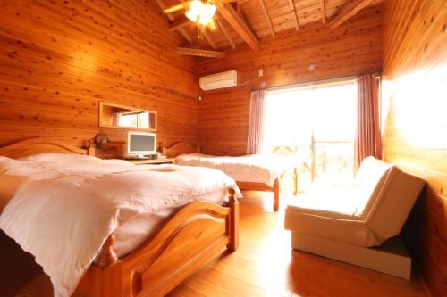 a bedroom with two beds and a chair and a window at Rest and Lodge Syou in Amami