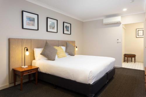 a bedroom with a large white bed and a table at Brisbane International Virginia in Brisbane