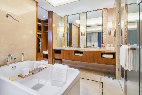 a bathroom with a tub and a large mirror at Jingling Shihu Garden Hotel  in Suzhou