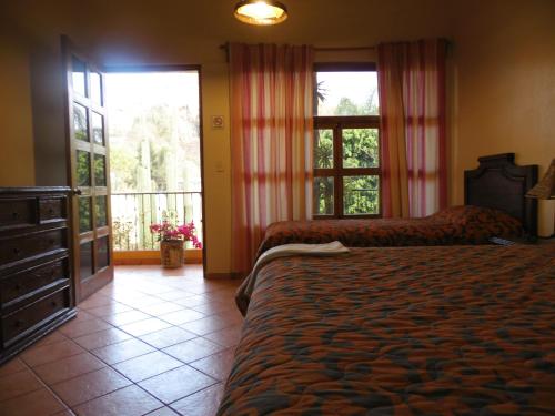 a bedroom with two beds and a large window at Hotel Plaza del Sol in Malinalco