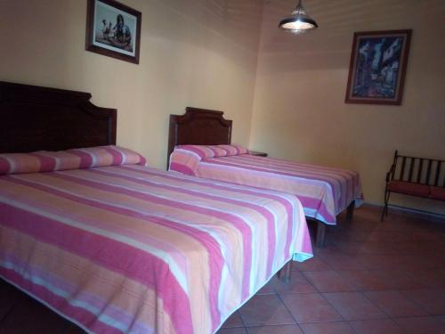 two beds in a hotel room with pink and purple sheets at Hotel Plaza del Sol in Malinalco