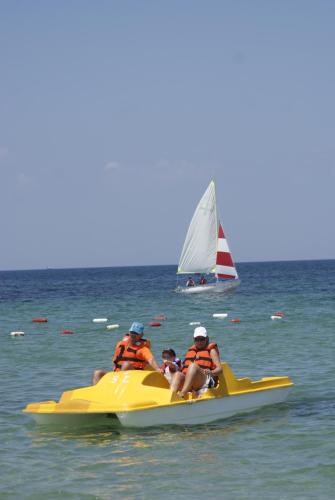 a group of people on a yellow jet ski in the water with a sail boat at El Mouradi Club Selima in Port El Kantaoui