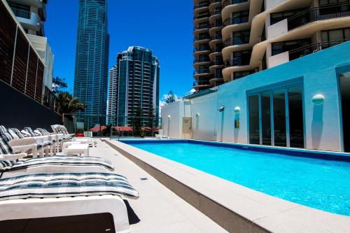 a swimming pool with chaise lounge chairs next to buildings at Beachcomber Resort - Official in Gold Coast