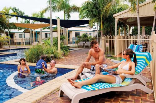 a man and a woman sitting on a bench in a swimming pool at Discovery Parks - Fraser Street, Hervey Bay in Hervey Bay