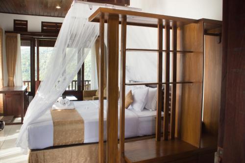 a bedroom with a bed with white sheets and a window at Maliana Homestay in Munduk