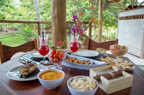 a table with plates of food and drinks on it at Canoé Brasil in Praia de Moitas