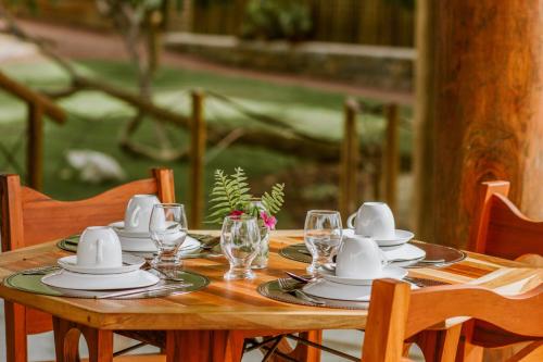 a wooden table with white dishes and glasses on it at Canoé Brasil in Praia de Moitas