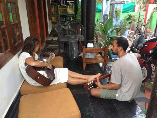 a man and a woman sitting on a couch with a guitar at Gone Coastal Homestay in Varkala