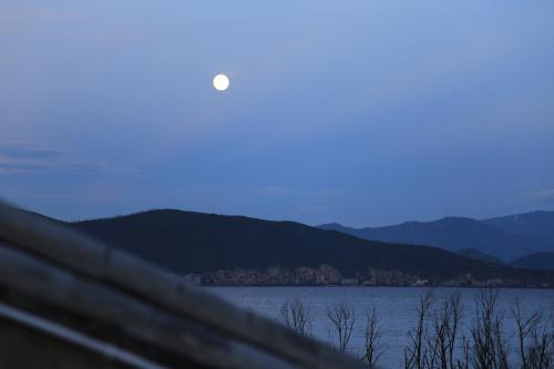 a moon rising over the water with a fence at Erhaike Seaview Inn in Dali